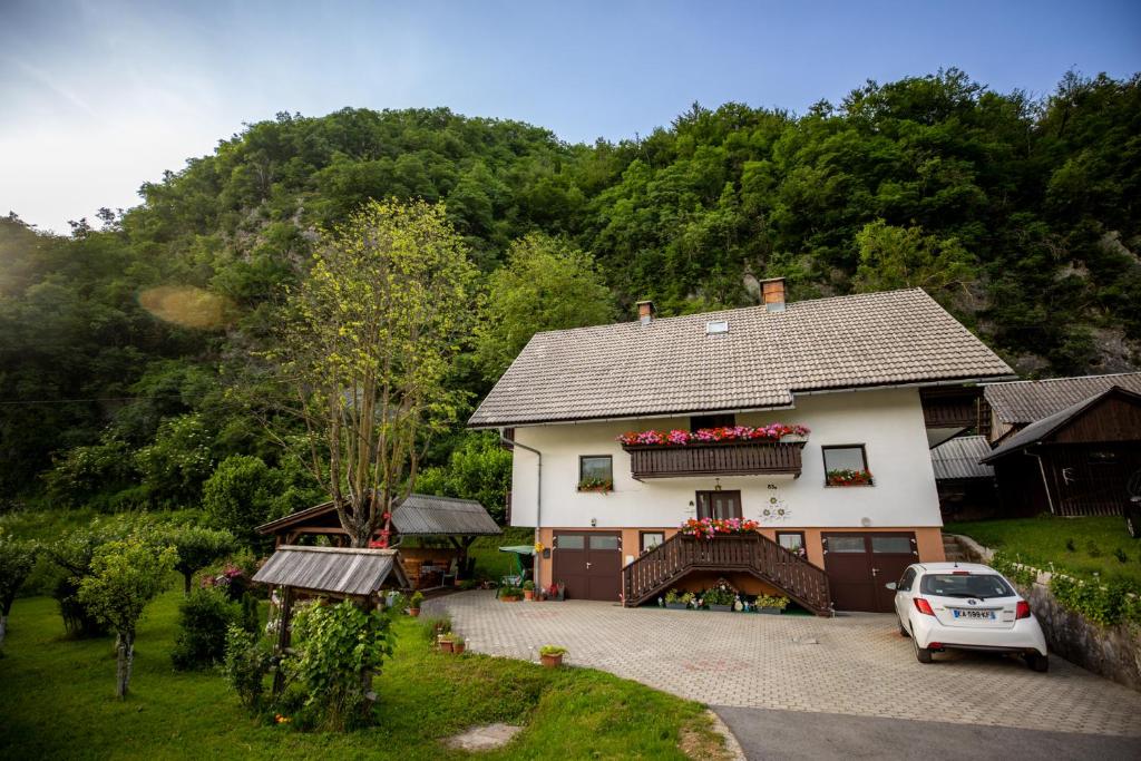 a white house with a car parked in front of it at Sobe Ličef in Bohinj