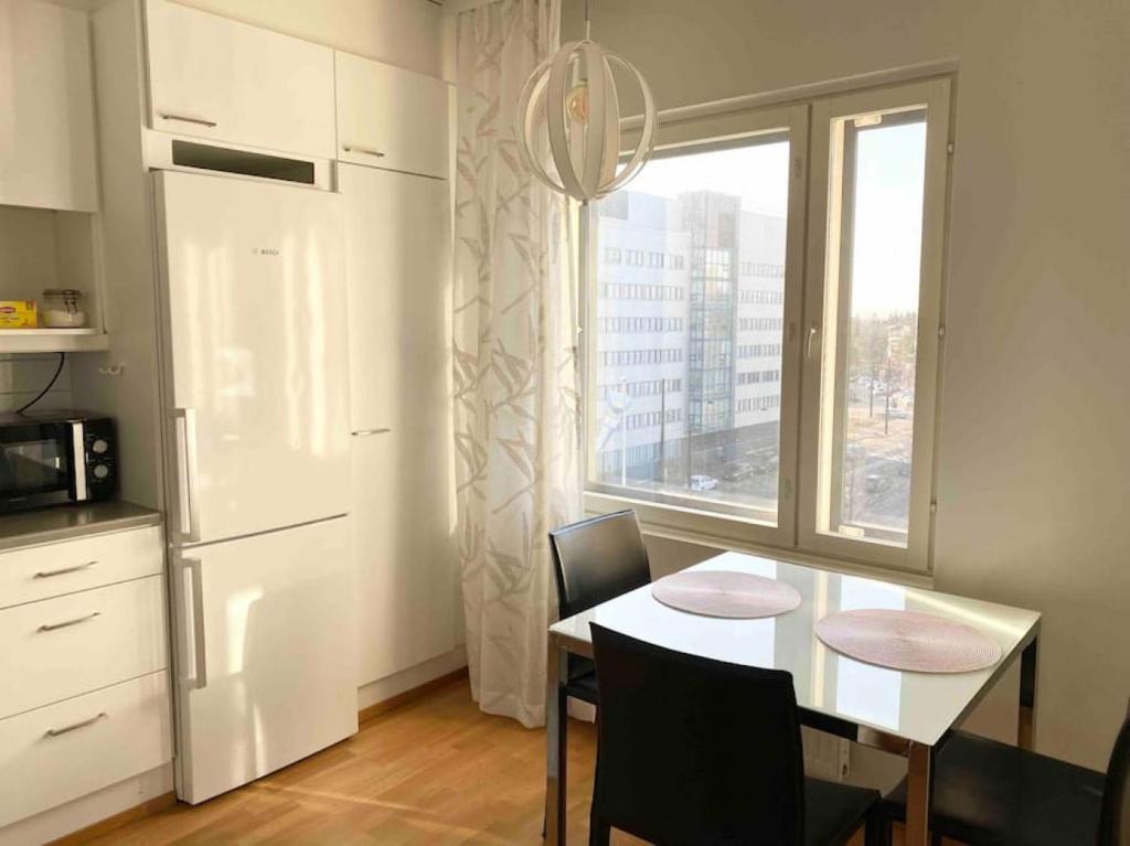 PASILA Modern flat centrally located في هلسنكي: مطبخ مع طاولة مع كراسي ونافذة