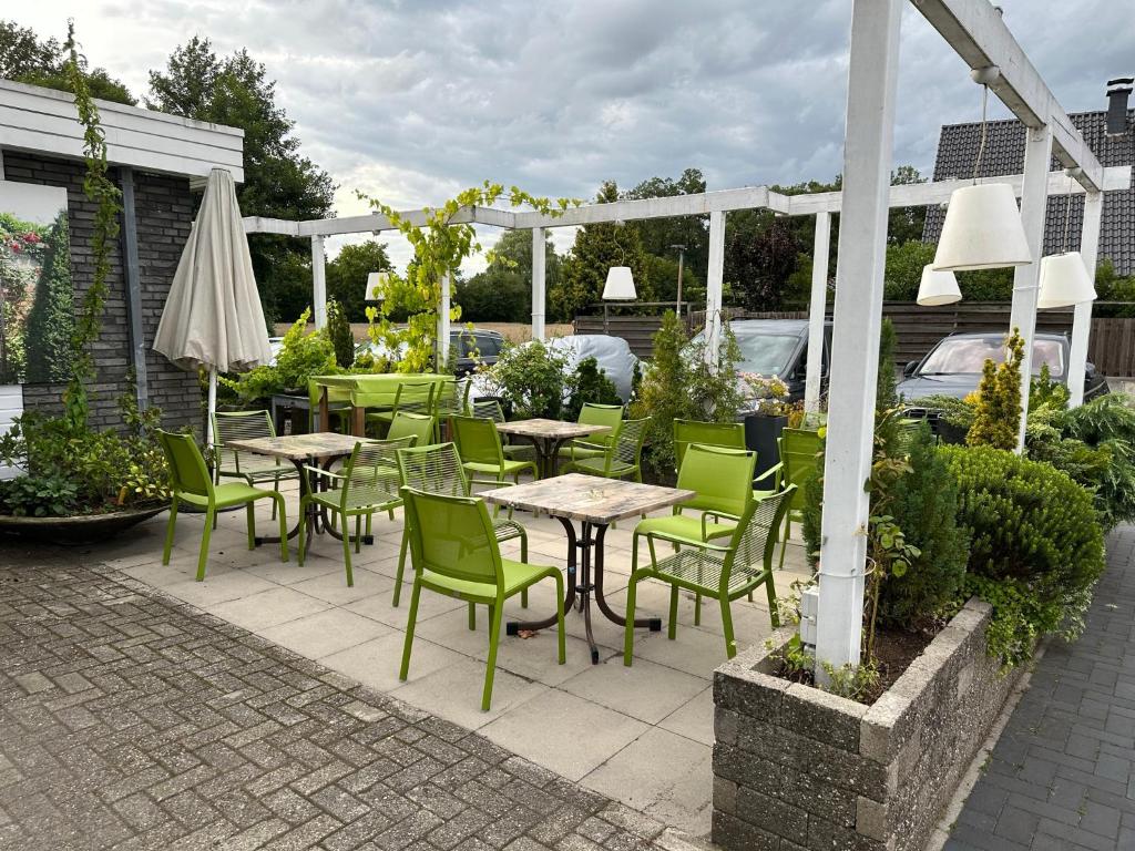 eine Terrasse mit Tischen, Stühlen und einem Sonnenschirm in der Unterkunft Haus Wijnen in Bad Bentheim