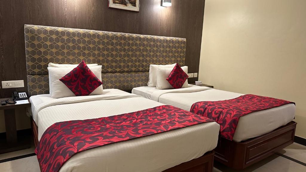 een hotelkamer met 2 bedden met rode kussens bij Hotel Annamalai International in Pondicherry