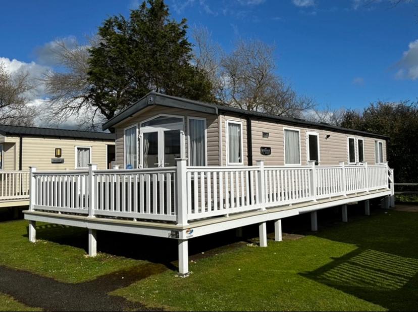 uma casa móvel com um alpendre e corrimão branco em Tenby - Kiln Park caravan hire em Pembrokeshire