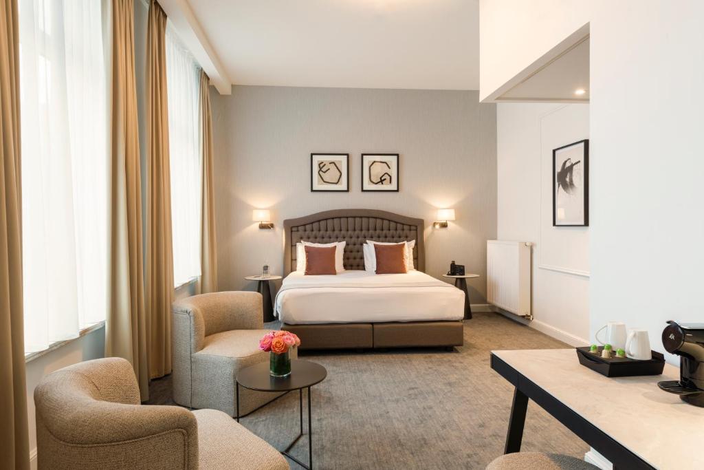 a hotel room with a bed and two chairs at Dukes' Academie Brugge - by Dukes' Hotel Collection in Bruges