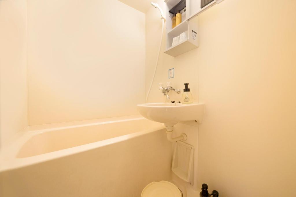 a bathroom with a sink and a toilet and a bath tub at Wafu-no-Yado MASUYA in Yamanouchi