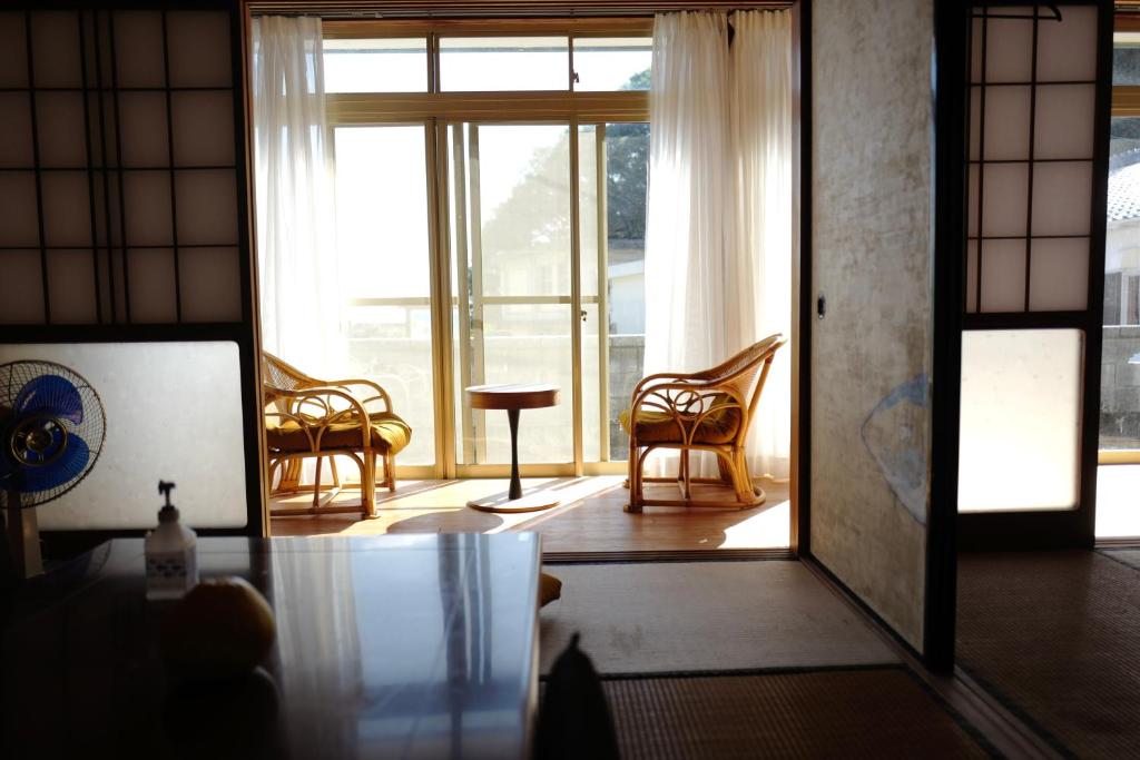 a living room with chairs and a large window at 魚の宿【海と西】 