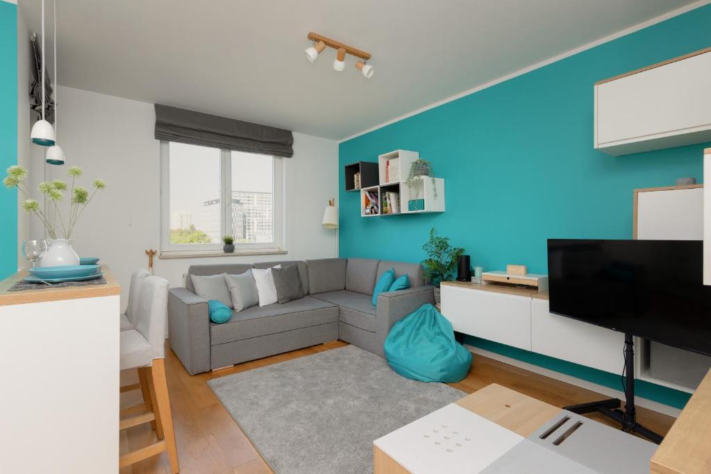 uma sala de estar com um sofá cinzento e uma parede azul em Metro Wilanowska Apartment with Parking by Renters em Varsóvia