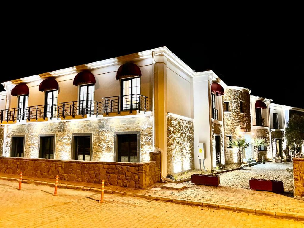 een groot wit gebouw 's nachts met lichten aan bij Hotel Panaya in Gokceada Town