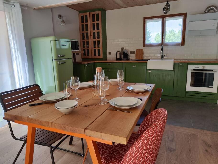 a wooden table in a kitchen with green cabinets at L'Oustalet d'Erine - spacieuse et climatisée in Albi