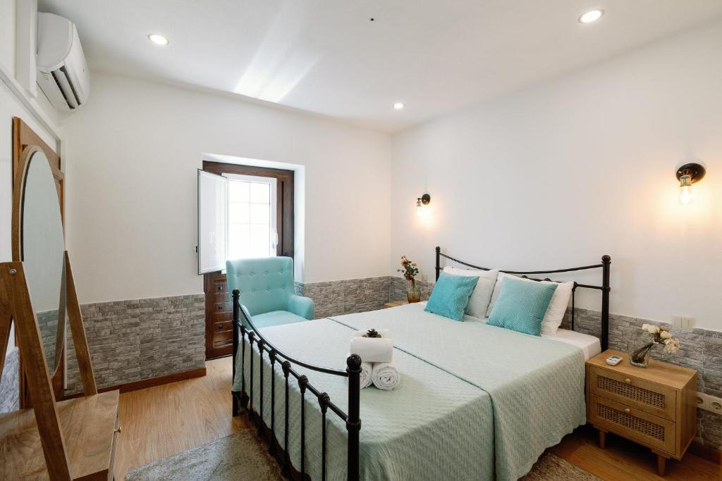 1 dormitorio con 1 cama y 1 silla azul en Casa do Javali, en Bragança