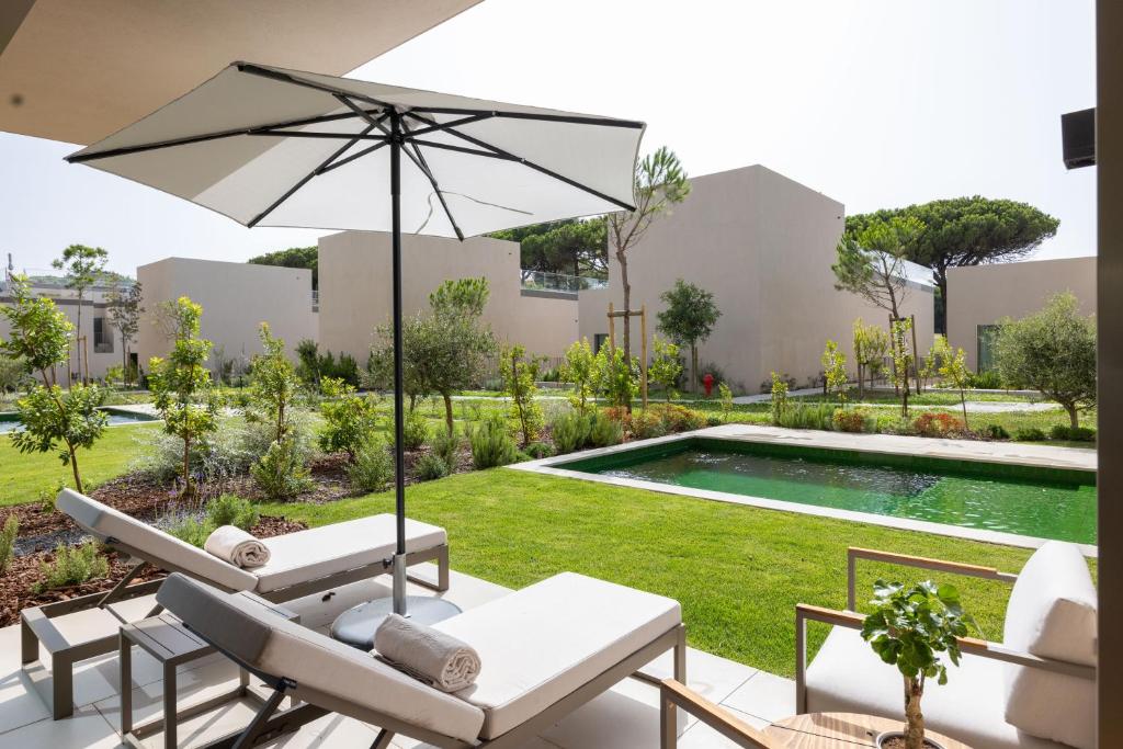 a patio with chairs and an umbrella and a pool at Marinha Prime in Cascais