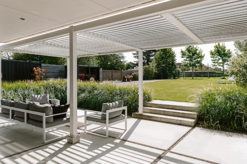 a white pergola on a patio with two chairs at BnB Manere in Grimbergen