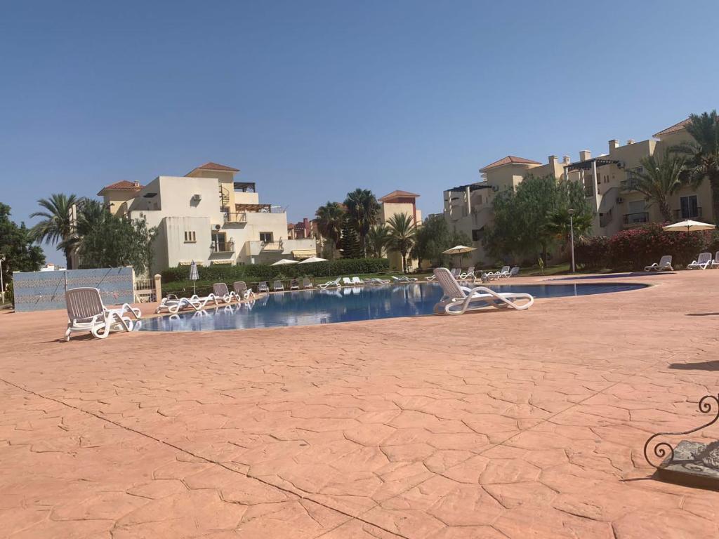uma piscina com espreguiçadeiras num resort em Ap6 em Saïdia