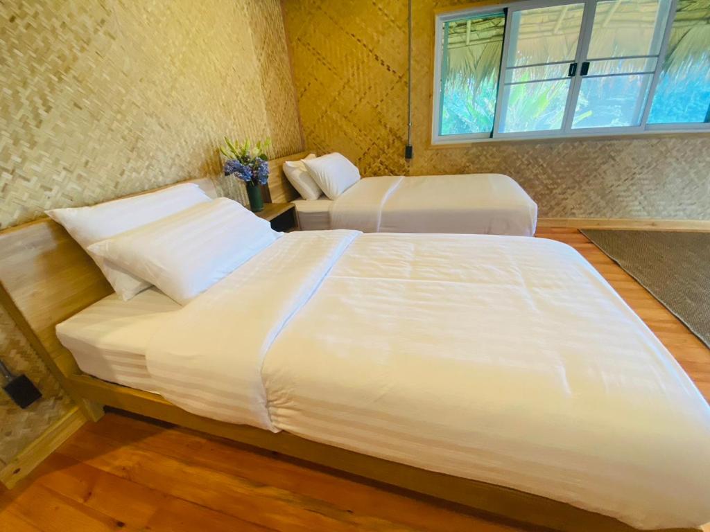 a bedroom with two white beds and a window at Daelorpu 1 แดลอปู in Ban Yang