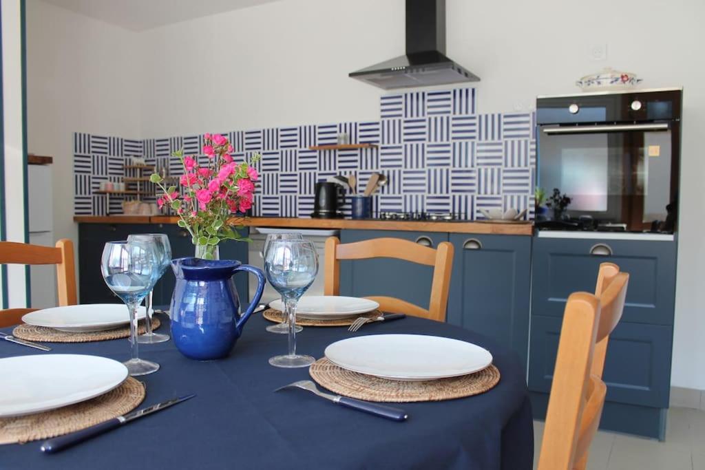 una mesa con platos y vasos y un jarrón con flores en Maison rénovée Atoué loc, en Fresnay-sur-Sarthe