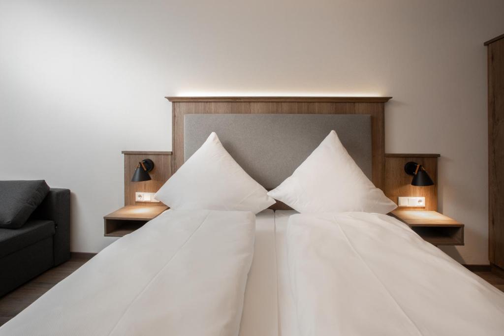 een slaapkamer met een bed met witte lakens en kussens bij Landgasthof Maier in Vilsbiburg