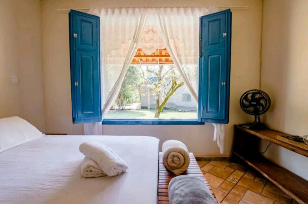 sypialnia z niebieskimi oknami i łóżkiem z ręcznikami w obiekcie Casinha aconchegante em meio a natureza w mieście Rio Acima