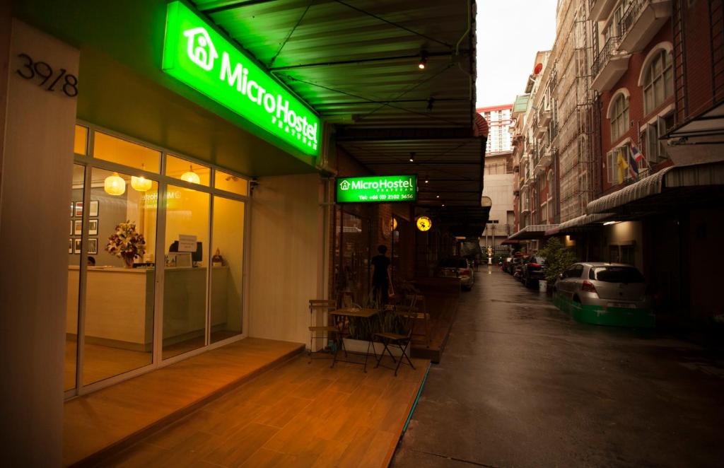 a store with a green sign on the side of a street at Micro Hostel in Bangkok