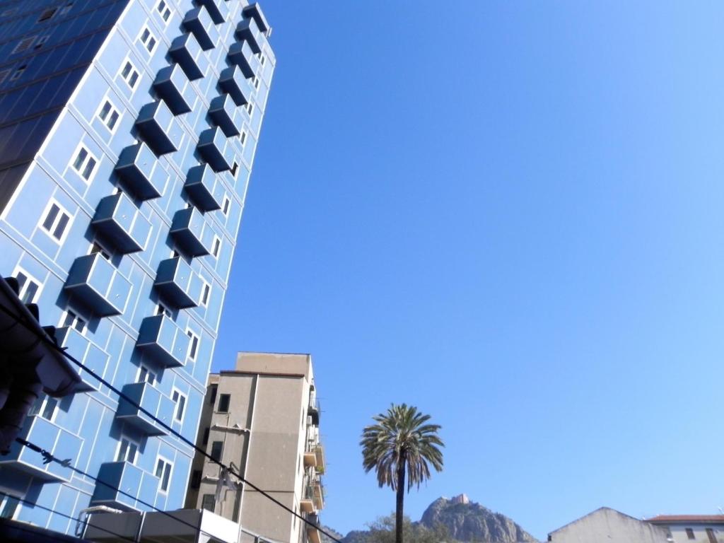 a tall building with a palm tree in front of it at Torreata Hotel & Residence in Palermo