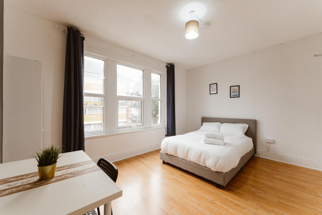 a bedroom with a bed and a table and window at Great Rooms in Plaistow - 147 in London