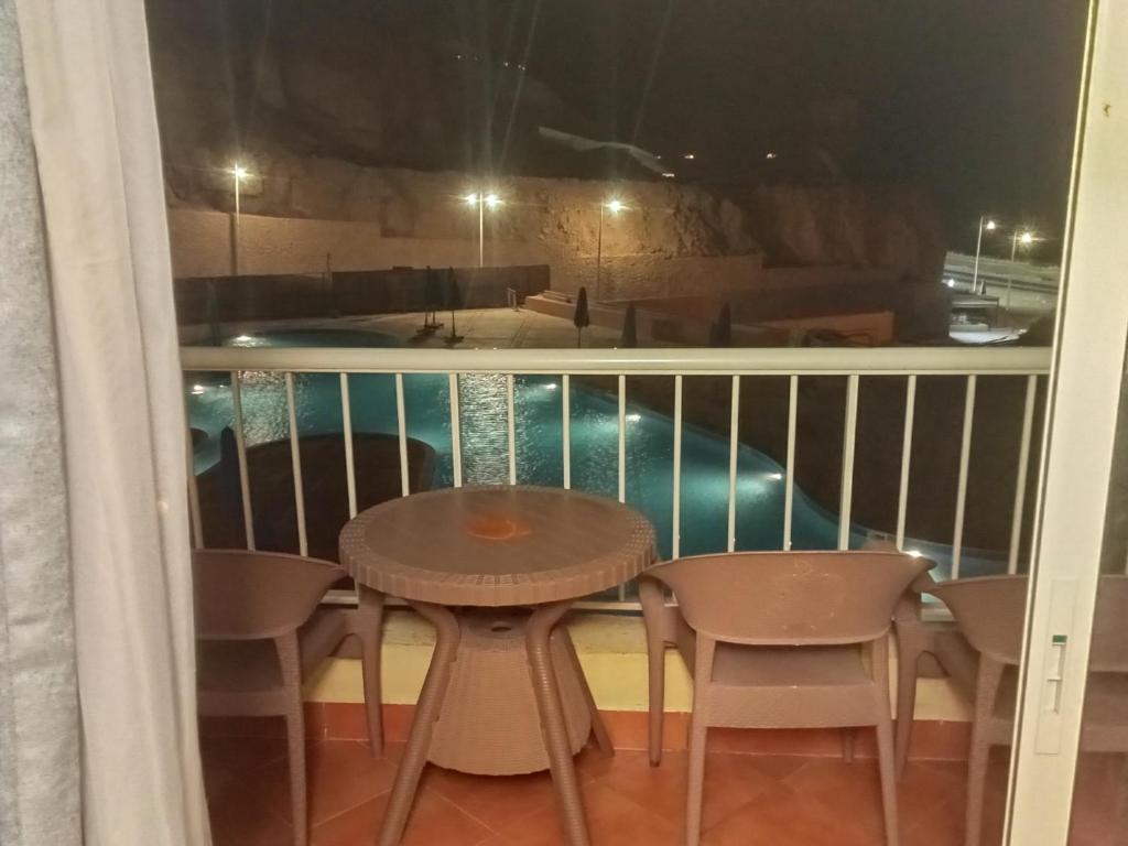 balcón con mesa, sillas y piscina en بورتو السخنه en Ain Sokhna