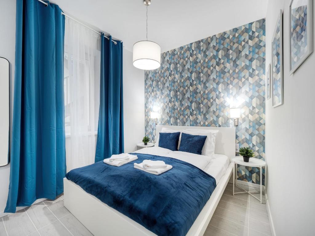 a bedroom with a blue and white bed and blue curtains at Central and New apartment with AC in Budapest