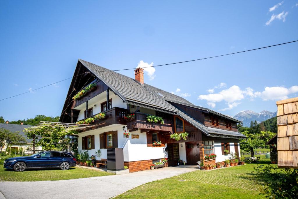 a house with a car parked in front of it at Apartmaji Preželj in Bohinj