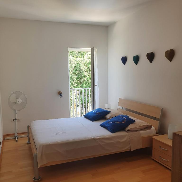 a bedroom with a bed with blue pillows and a window at Dee&#39;s House and Pool in Labin