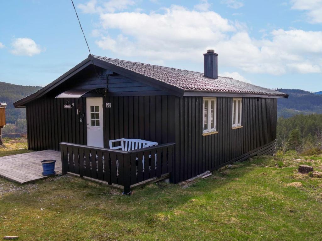 una pequeña casa negra con un porche en el césped en Chalet Solbu - SOW087 by Interhome, en Fossdal