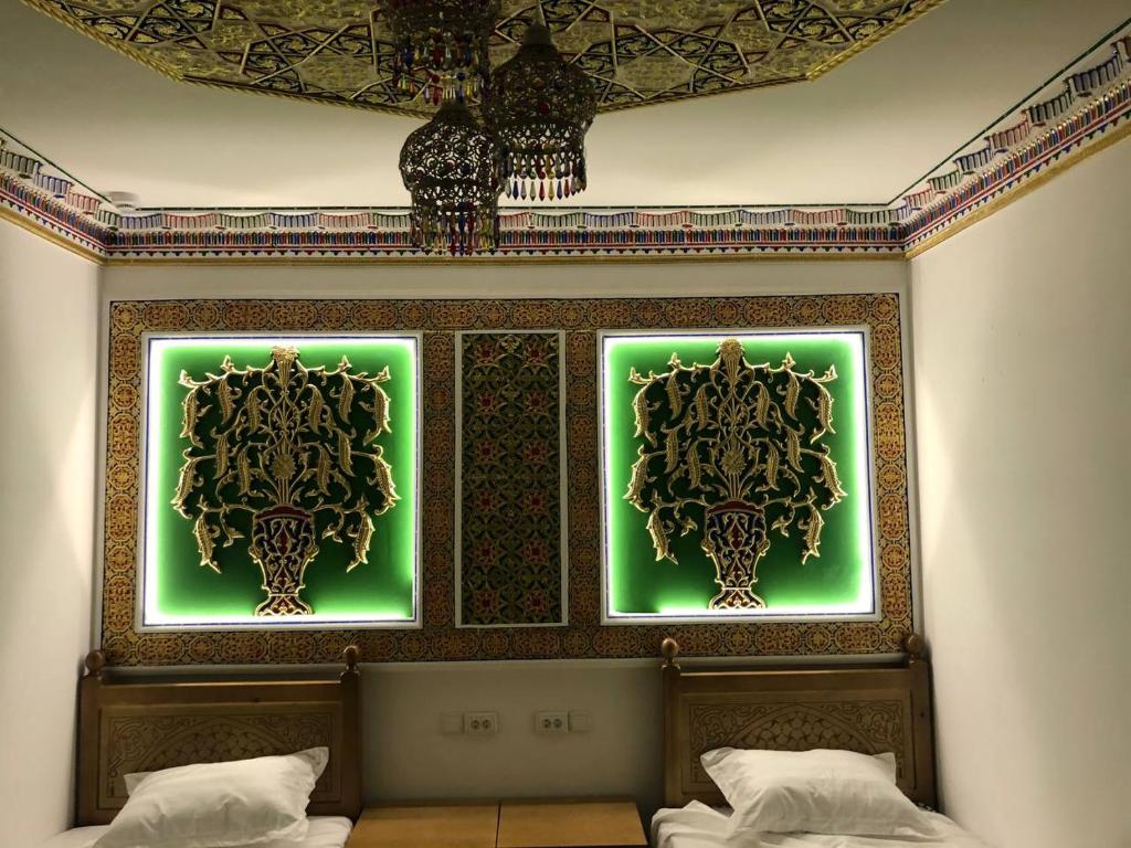1 dormitorio con 2 pinturas verdes en la pared en Tasvir Hotel, en Bukhara