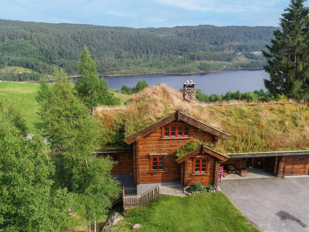 a log cabin with a grass roof with a lake at Chalet Lindefjeldbu - SOW144 by Interhome in Fossdal