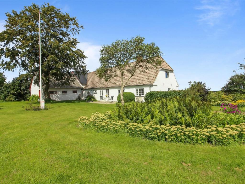 una casa blanca con un patio verde con un árbol en Holiday Home Ulv - 20km from the sea in Western Jutland by Interhome, en Ribe