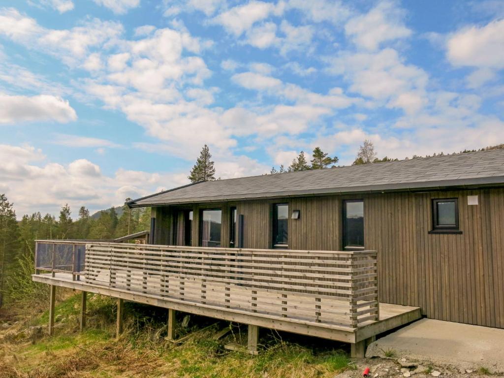 a house with a large wooden deck in the grass at Chalet Kosetoppen - SOW145 by Interhome in Fossdal