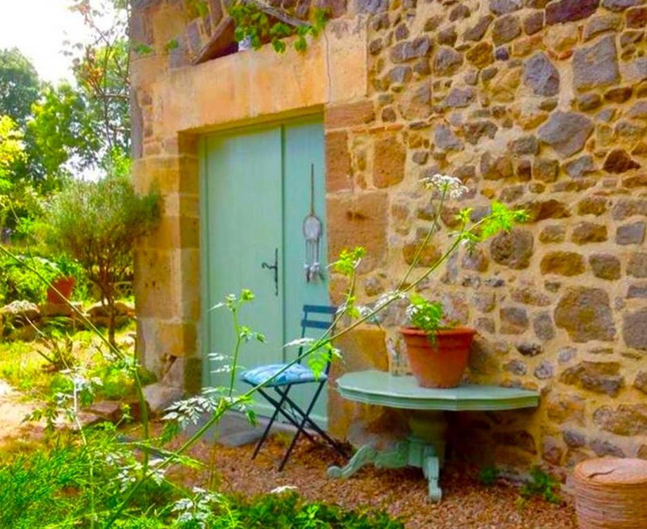 une porte d'un bâtiment en pierre avec une table et une chaise dans l'établissement Domaine Charente - Familyroom Gypsy with garden (with external toilet & shower house), à Mazières