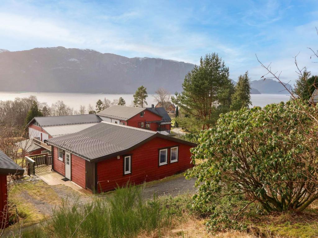 a red house with mountains in the background at Holiday Home Havbris - FJS152 by Interhome in Sørbø