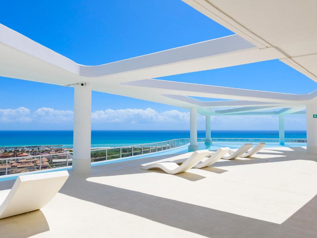 eine Reihe weißer Stühle auf einem Balkon mit Meerblick in der Unterkunft Apartment Gran Canet by Interhome in Canet d'en Berenguer