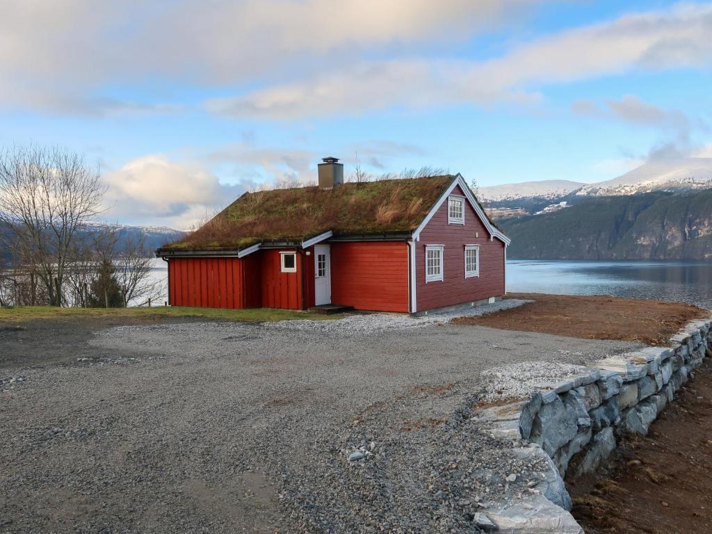 a red house with a grass roof on a lake at Chalet Krampehaugen - FJS046 by Interhome in Utvik