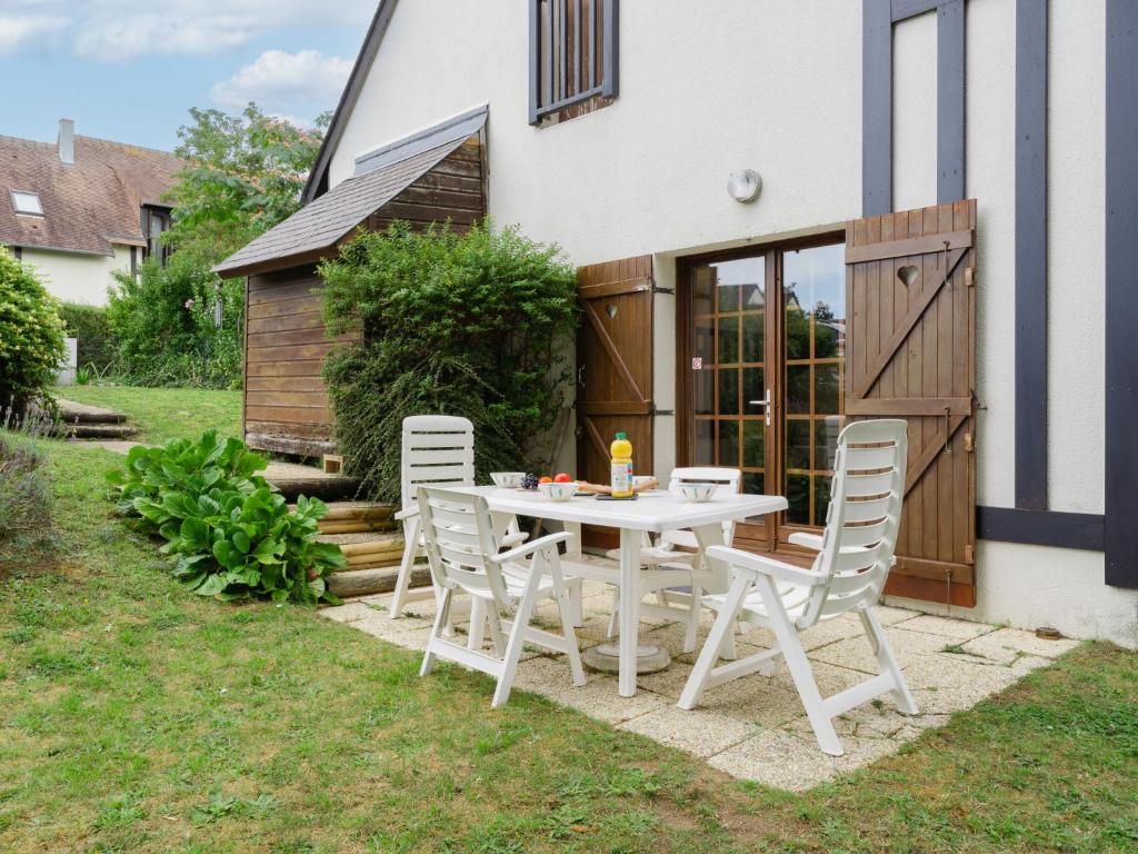 uma mesa branca e cadeiras em frente a uma casa em Holiday Home La Cour du Moulin by Interhome em Houlgate