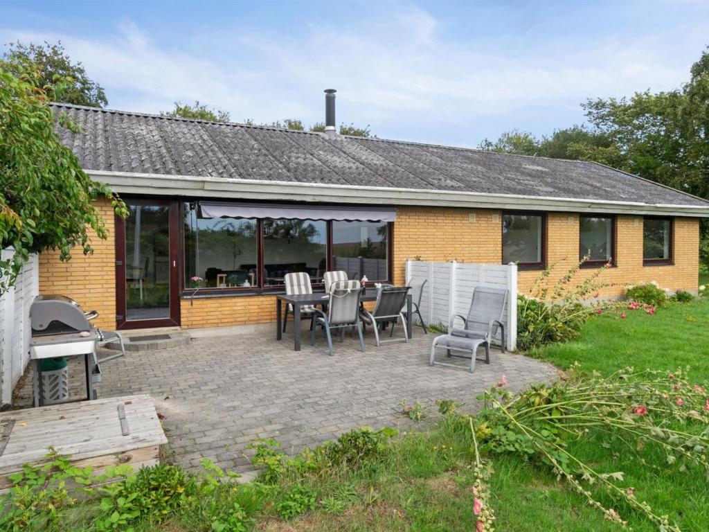 a patio with a table and chairs in front of a house at Holiday Home Kolle - 3-2km from the sea in Bornholm by Interhome in Vester Sømarken