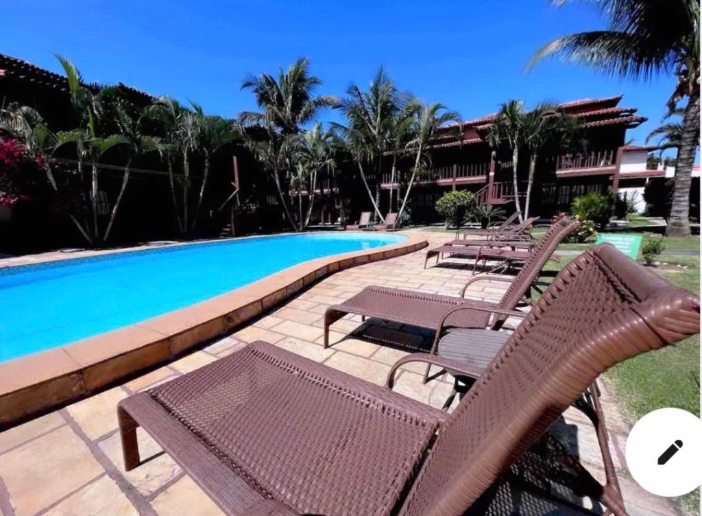 布希奧斯的住宿－Geribá Apart Hotel Internacional Buzios，一组椅子,位于游泳池旁