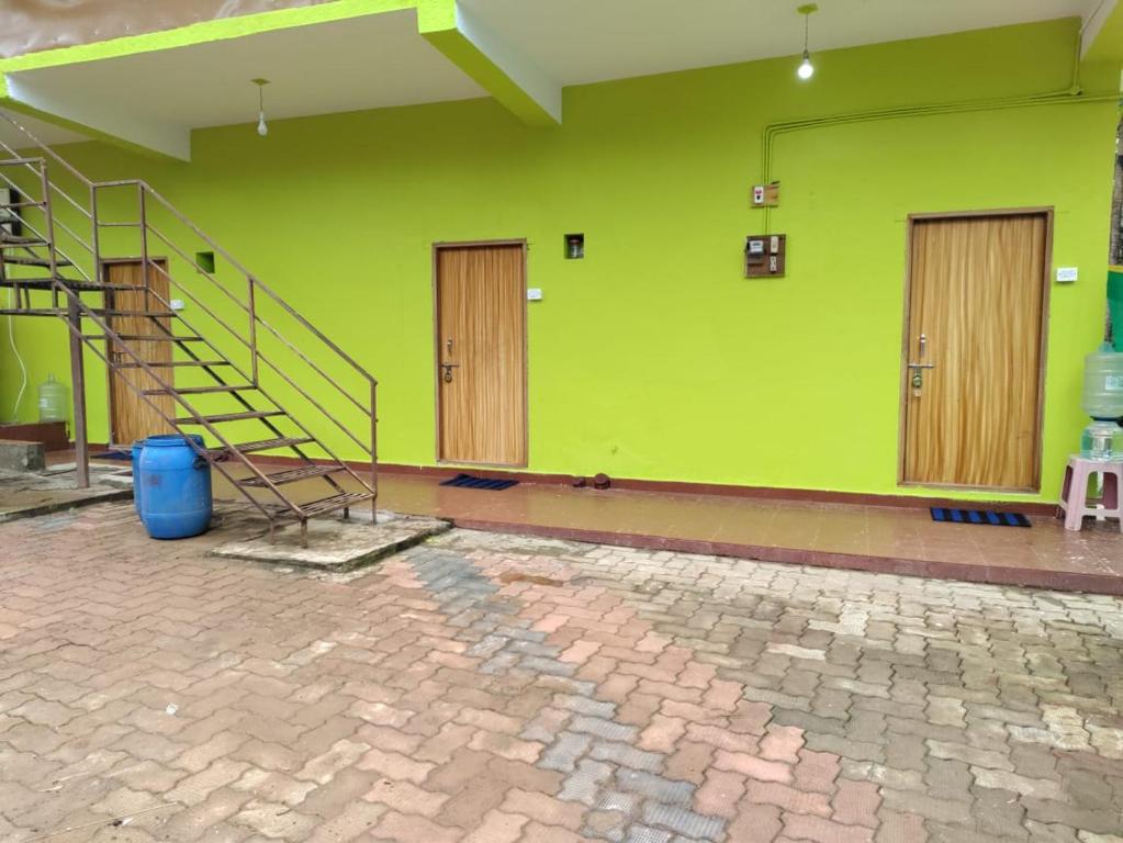 KUKKE GUEST ROOM في Subrahmanya: جدار أخضر بأبواب خشبية ودرج