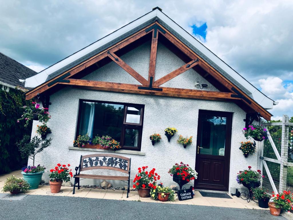 una casa bianca con una panchina davanti di Cargagh Cottage a Annacloy