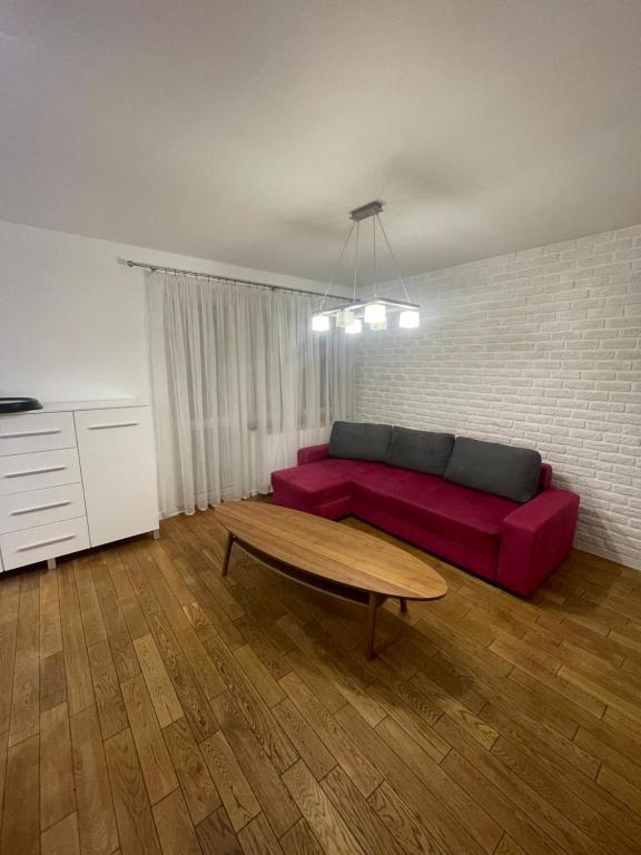 sala de estar con sofá rojo y mesa en Apartament Szczytno, en Szczytno