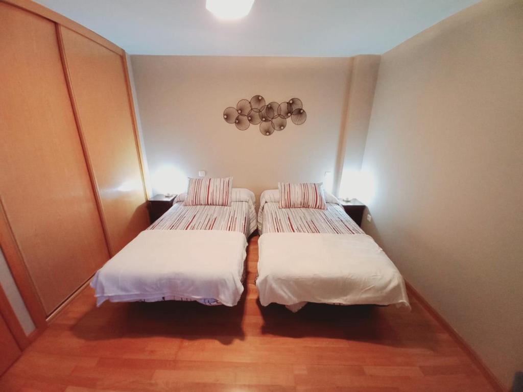 2 camas en una habitación pequeña con sábanas blancas en Apartamento centrico para 3 con Wifi y garaje, en Tudela de Duero