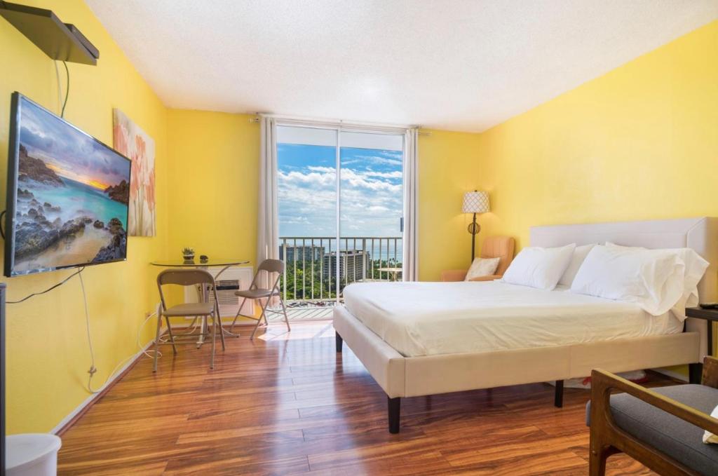 a bedroom with yellow walls and a bed and a balcony at Relaxing Ocean View Boutique Condo - 20F in Honolulu