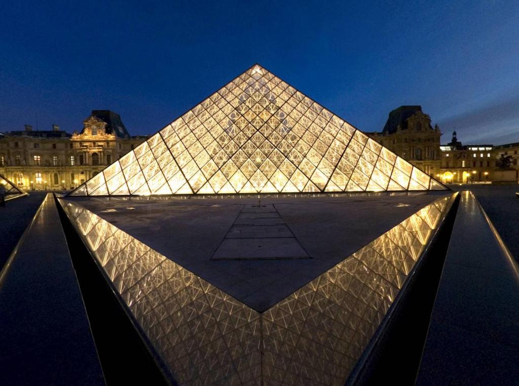 un bâtiment en forme de pyramide avec des lumières allumées la nuit dans l'établissement Jabeen's House Bedroom 2, à Bezons