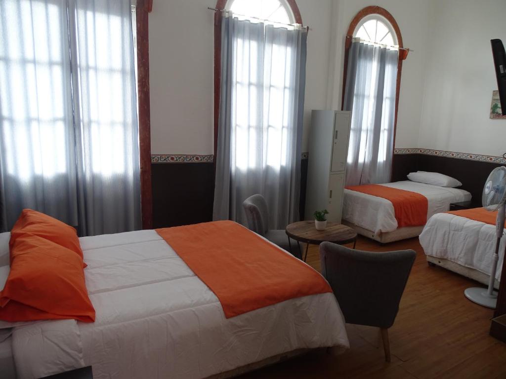 1 dormitorio con 2 camas, mesa y sillas en Gran Casona Hostal, en Iquique