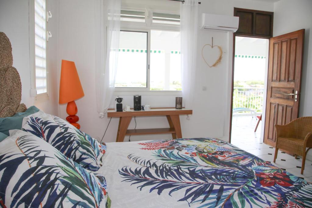 a bedroom with a bed with a tropical patterned sheets at Villa Théo , chambre d'hôtes , petit déjeuner in Sainte-Anne