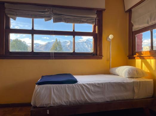 um quarto com uma cama e uma janela com montanhas em Pintó Casa Hostel & Bar em Esquel