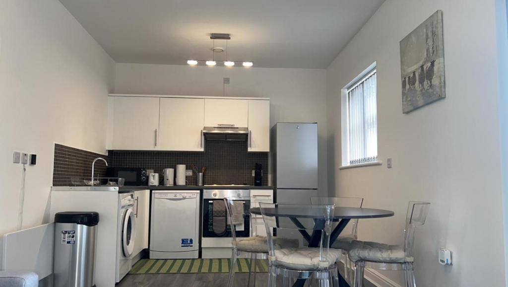 una cocina con electrodomésticos blancos, mesa y sillas en Luxury apartment in dudley en West Bromwich