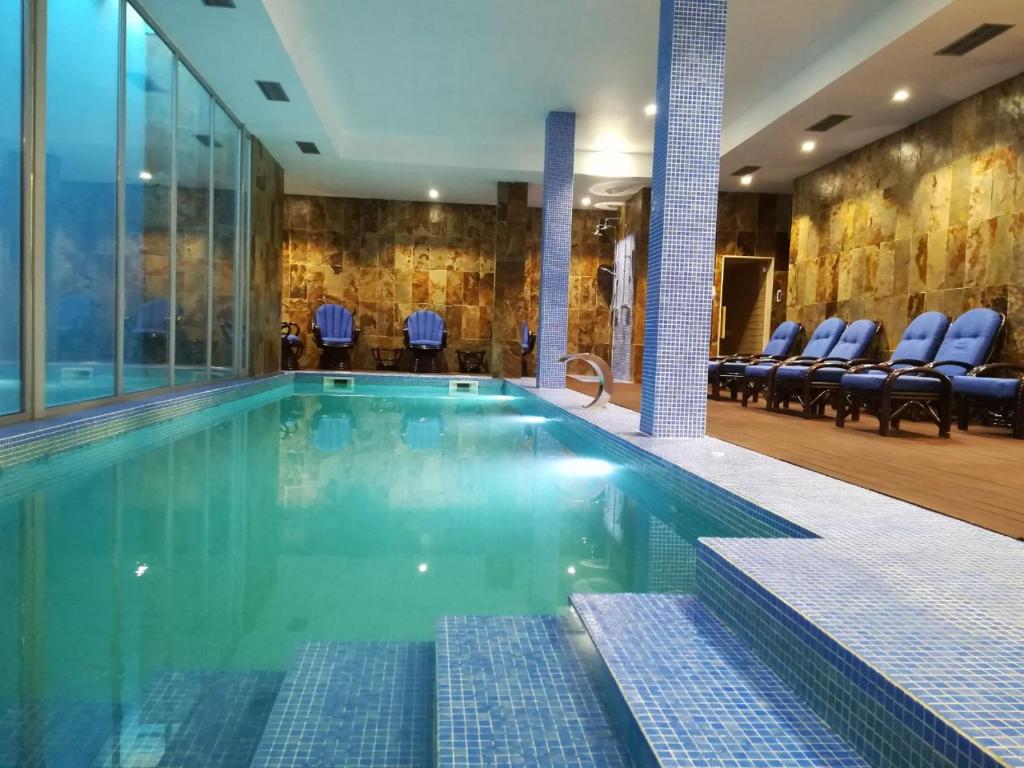 a swimming pool in a hotel with blue chairs at Hotel Ibn-Arrik in Coimbra