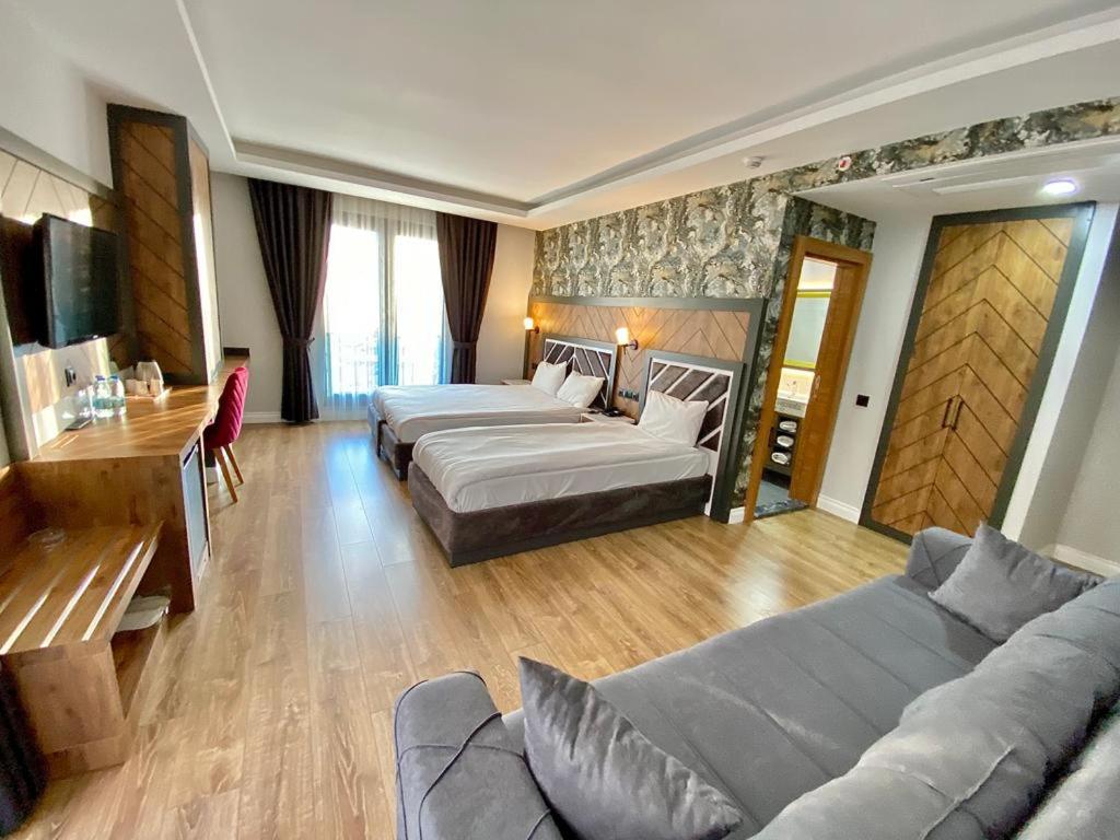 Habitación de hotel con 4 camas y sofá en Grand Nergiz Otel, en Antalya